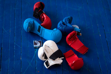 Colored protective gloves and mouthguard for martial arts on the blue wooden floor of the gym.の写真素材