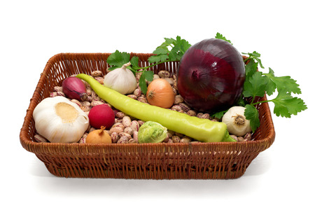 A basket full of beans, onion, garlic with green peppers, radishes, cabbage and parsley isolated on white backgroundの写真素材