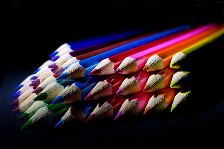 Macro Shot of Sharpened Colorful Pencils Against Black Background. Instruments for writing or drawing, consisting of a thin stick of graphite enclosed in a long thin piece of woodの写真素材