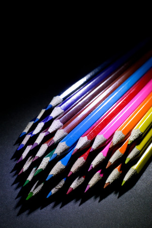 Macro Shot of Sharpened Colorful Pencils Against Black Background. Instruments for writing or drawing, consisting of a thin stick of graphite enclosed in a long thin piece of woodの写真素材