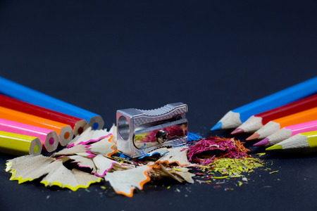 Sharpened Colorful Pencils Against Blunt Pencils with Metallic Pencil Sharpener and Colorful Pencil Shavings on Black Backgroundの写真素材