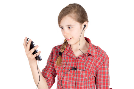 Side View of Smiling Young Girl With Earbuds  Listening to Music on Her Cellphone Isolated on White Background HalfLength Studio Shotの写真素材