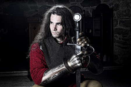 Portrait of Serious Knight in Chain Mail With Metal Gloves and Sword Looking Away, Half Length Shot