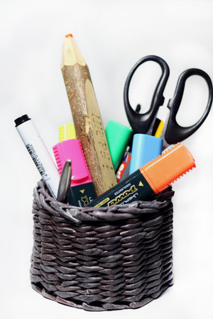 School and office supplies in a wicker basket on a white background