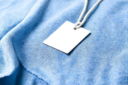 Blank white price tag on blue jeans background. Closeup.の写真素材