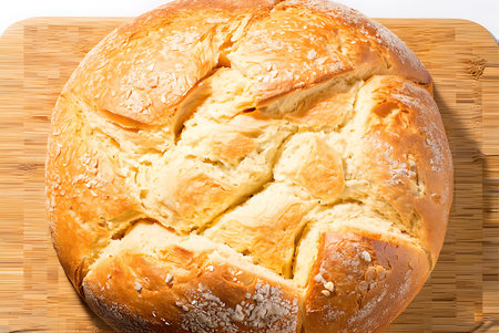 Freshly baked bread with sesame seeds on wooden cutting board.