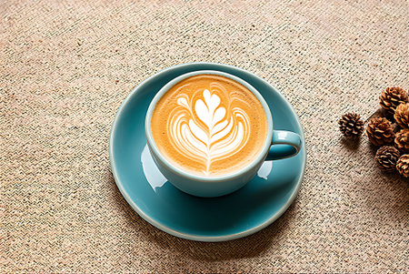 Cup of coffee with latte art on sackcloth background.