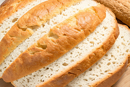 Close-up of sliced bread on a wooden board. Whole background.