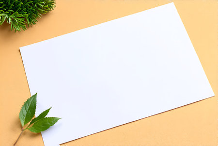 White paper sheet and green plant on orange background with copy space.