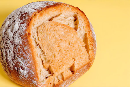 Freshly baked bread with icing sugar on yellow background, closeup