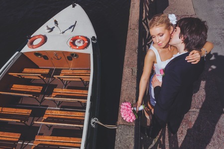 Bride and groom on the background of recreational river boats. View from above. The groom kisses the brideの写真素材
