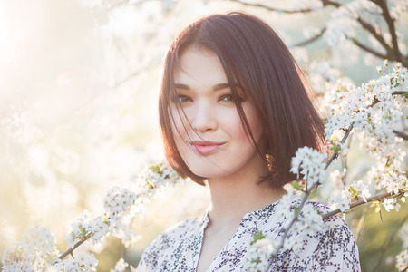 beautiful young woman in blooming cherry blossoms garden