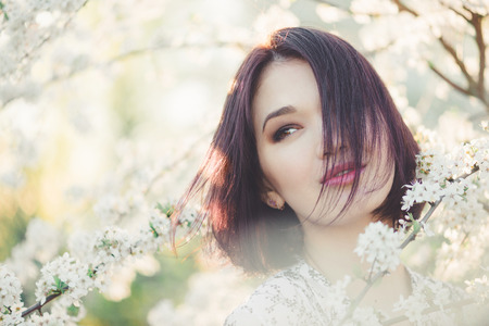 beautiful young woman in blooming cherry blossoms garden