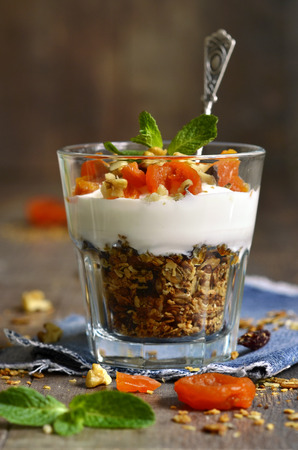 Dessert from granola,yogurt,nuts and dried apricot in a glass.の写真素材