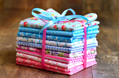 Pile of colorful folded textile on a wooden table.