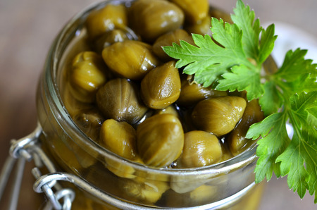 Capers in a jar on wooden table.の写真素材