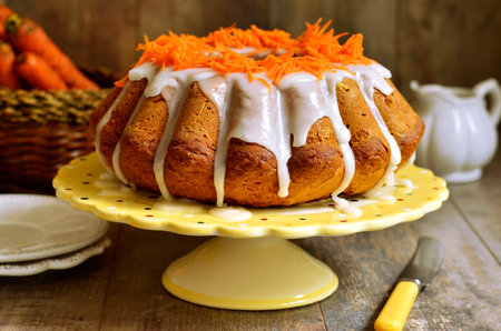 Carrot cake with sugar glaze on rustic background.