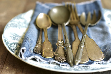 Old cutlery on a vintage plate on wooden table.の写真素材