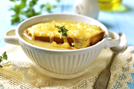 French rustic onion soup on a blue wooden table.の写真素材