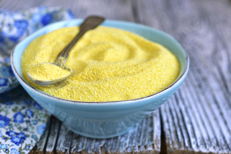 Dried polenta in a blue vintage bowl on a wooden table.の写真素材