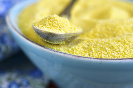 Dried polenta in a blue vintage bowl on a wooden table.の写真素材