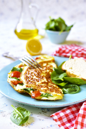 Omelet with tomatoes and spinach on a blue vintage plate.の写真素材
