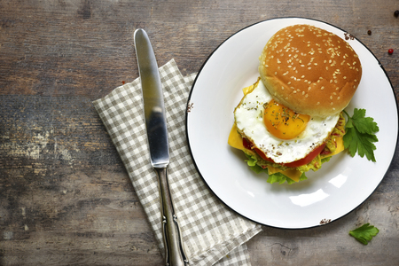 Vegetarian burger with guacamole and roasted egg on a vintage plate on a wooden background.Top view.の写真素材