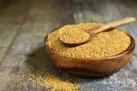 Brown sugar in a wooden bowl on a rustic background.の写真素材