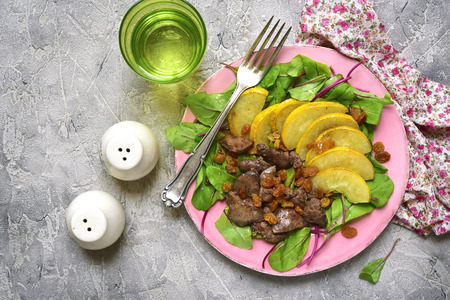 Warm autumn salad chard leaves,chicken liver,caramelized pear and raisins on a grey concrete or stone background.Top view.の写真素材