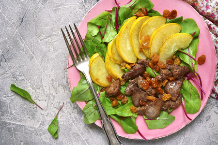 Warm autumn salad chard leaves,chicken liver,caramelized pear and raisins on a grey concrete or stone background.Top view.の写真素材
