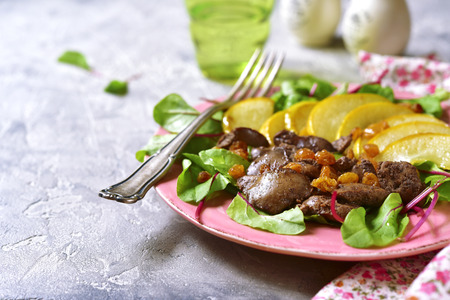 Warm autumn salad chard leaves,chicken liver,caramelized pear and raisins on a grey concrete or stone background.の写真素材