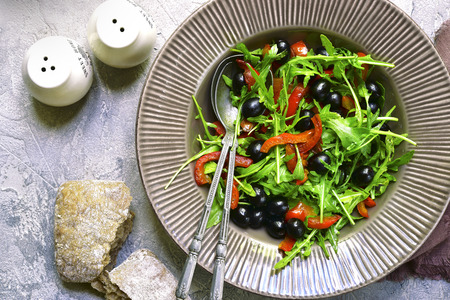 Salad with arugula,black olives and grilled bell pepper on a grey rustic concrete,stone or slate background.Top view.の写真素材