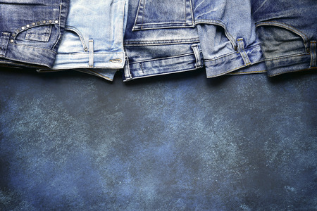 Variety of man and wooman blue jeans on a grunge slate, stone or concrete background.Top view with space for text.の写真素材