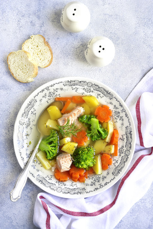 Vegetable soup with salmon in a vintage bowl on a grey slate,stone or concrete background.Top view.の写真素材