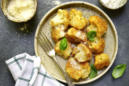 Roasted cauliflower with yogurt sauce and cheese on a plate on a grey slate,stone or concrete background.Top view.の写真素材