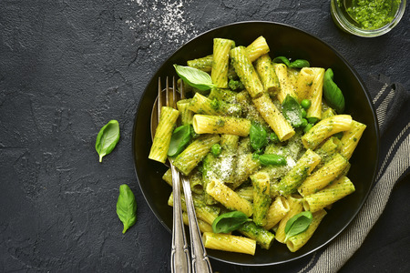 Pasta with sauce pesto and green pea in a black bowl on a slate,stone or concrete background.Top view.の写真素材