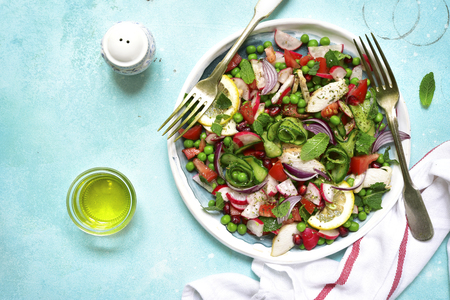 Summer colorful vegetable salad with chicken and mint on a craft plate on light blue slate,stone or concrete bsckground.Top view.の写真素材