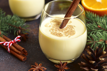 Winter spicy hot drink eggnog in a glasses on a dark slate,stone or concrete background.の写真素材