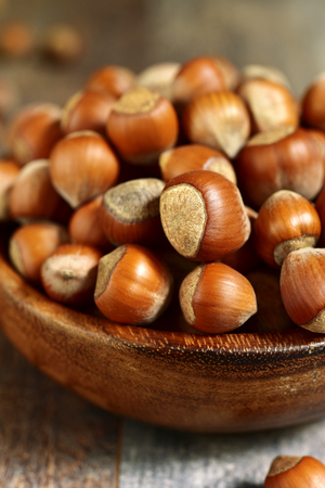 Heap of hazelnuts in a wooden bowl on a rustic background.の写真素材