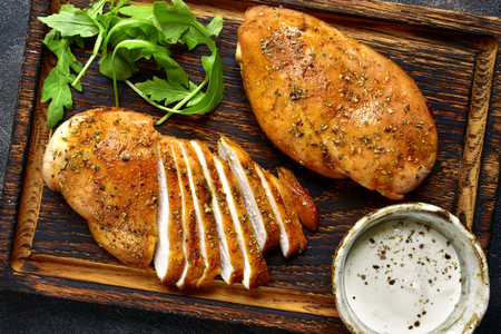 Grilled chicken breast in a sweet and sour marinade with yogurt sauce on a wooden cutting board.Top view.の写真素材