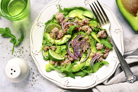 Tuna salad with avocado and arugula on a white vintage plate over light slate, stone or concrete background.Top view.の写真素材