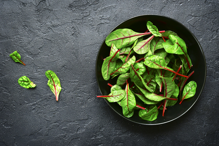 Chard leaves  in a bowl on a black slate, stone or concrete background.Top view with copy space.の写真素材