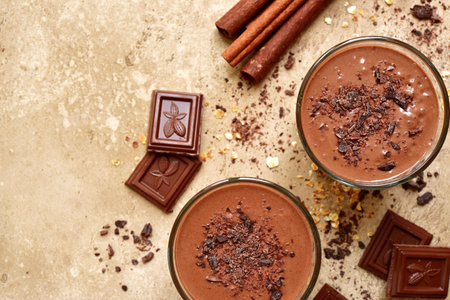 Chocolate banana smoothie with cinnamon in a glasses over beige (sand) slate, stone or concrete...