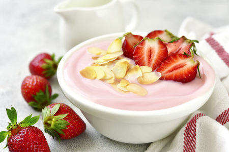Natural strawberry yogurt with fresh berry and mint in a white bowl on a light slate, stone or concrete background.の写真素材