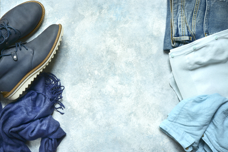 Woman clothing set in a blue color - jeans, blouse, shirt, boots and accessories on a light blue slate, stone or concrete background.Top view with copy space.の写真素材