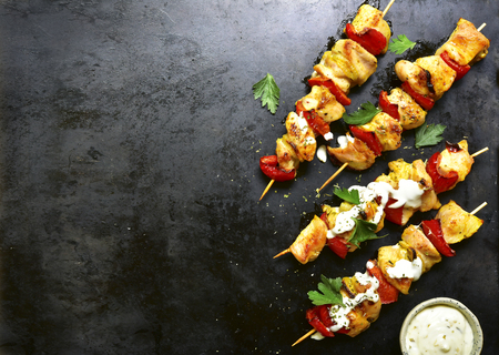 Chicken skewer kebab with bell pepper and yogurt sauce on a black metal, slate or stone background.Top view with copy space.の写真素材