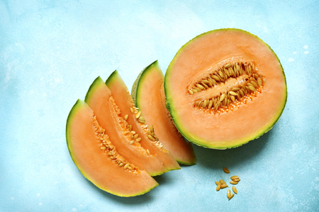 Raw organic tuscan melon cantaloupe on a light blue slate, stone or concrete background.Top view with copy space.の写真素材