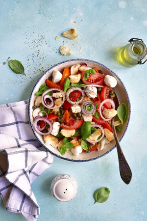 Traditional italian tomato salad panzanella with mozzarella balls, capers, onion and bread.Top view.の写真素材