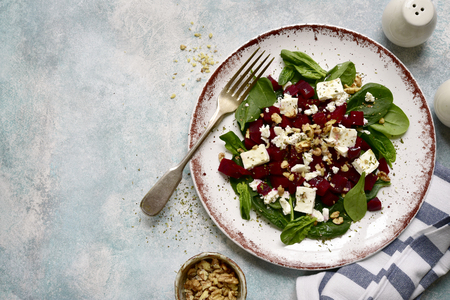 Autumn beetroot salad with spinach, feta cheese and walnuts on a plate over light blue slate, stone or concrete background.Top view.の写真素材