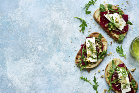Toasts with beet root, feta cheese, arugula and walnut on a light blue slate, stone or concrete background.Top view with copy space.の写真素材